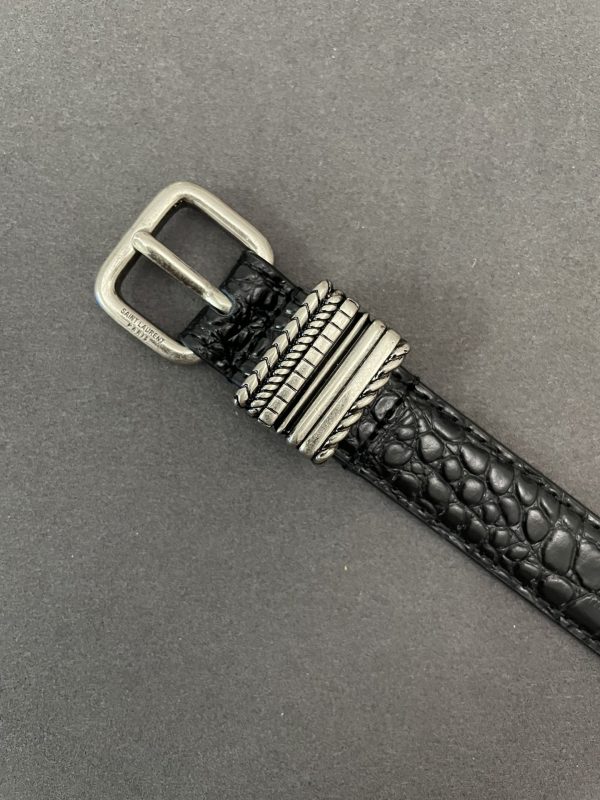 The square buckle of the YSL belt is engraved with the SAINT LAURENT PARIS logo.